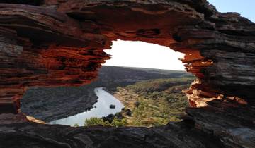 Natural rock formation with a window-like opening revealing a river.