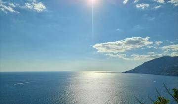 Expansive ocean view with the sun shining brightly in a clear sky.