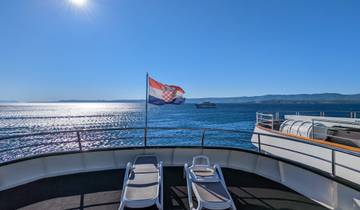 Back view from a yacht with the Croatian flag, ocean, and coast.