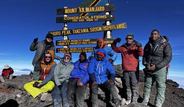 Group celebrating at the Uhuru Peak summit marker.