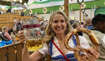 Woman in traditional dress holding a large beer mug and pretzel.