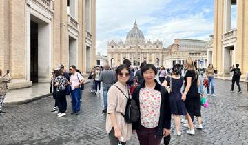 Tourists posing with St. Peter's Basilica in the background.
