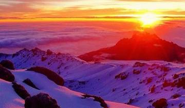 Sunrise over a snow-covered mountain landscape with a sea of clouds.