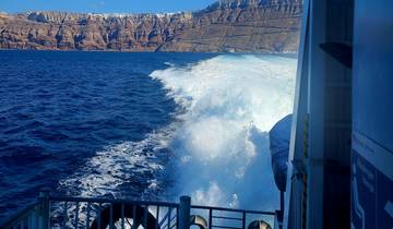 View from a boat with waves and rocky cliffs in the distance.