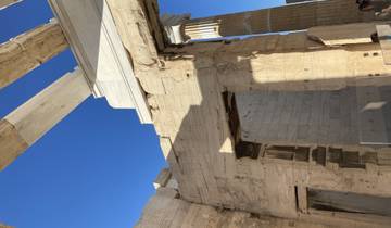 Ancient ruins with blue sky viewed from below.