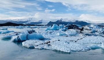 Glacial lagoon with floating icebergs and snowy mountains.