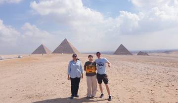 Three people posing in front of the pyramids.