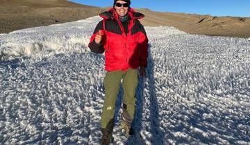 Person standing on a snowy terrain with mountainous background.