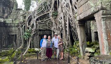 Group of people standing in front of an ancient temple with large trees.