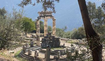 Ruins of a Greek temple with mountains in the background.