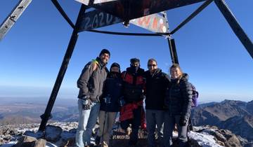 Group of people at the peak of a snowy mountain.