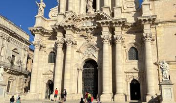 Facade of a baroque cathedral with people.