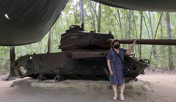 Person posing with a historic tank under a canopy.