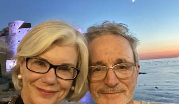 Couple taking a selfie with a waterfront and castle in the background.