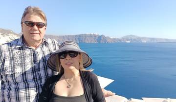A couple posing with a sea and cliffs in the background.