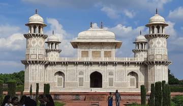 White marble mausoleum with intricate decorations and people.