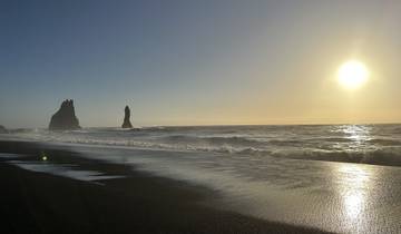 Black sand beach with sea stacks at sunrise.