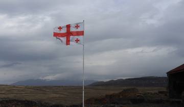 Georgian flag waving with mountains in the background.