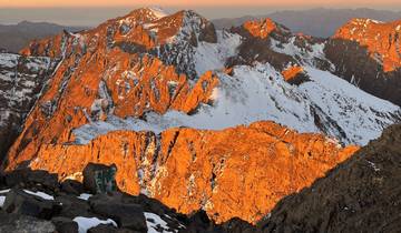 Sunlit mountains with snow patches creating a dramatic landscape.