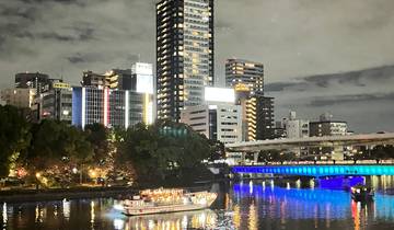 Night view of a cityscape with a lit-up boat on the river.