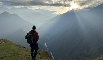 Hiker with a view of mountains and the sun.