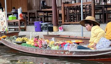 A vendor in a boat selling fruits at a floating market.