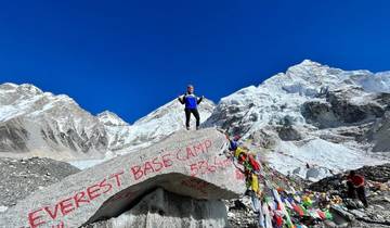 Person standing on a rock at Everest Base Camp with snowy mountains in the background.