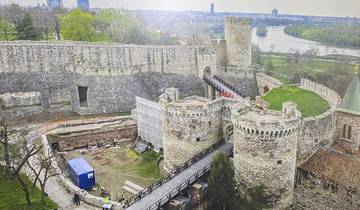 Medieval fortress with stone towers and walls, overlooking a river.