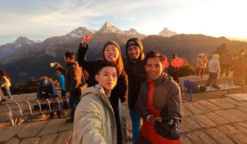 Group of people posing with a scenic mountain backdrop at sunrise.