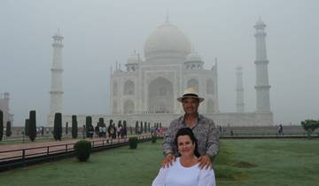 Couple posing with the Taj Mahal as a backdrop on a misty morning.
