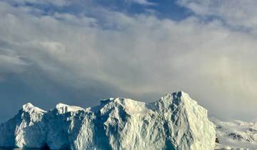 Massive iceberg with a dramatic cloudy sky.