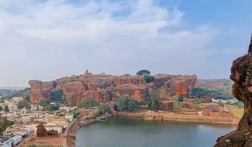 Large rock formation by a lake with a small town below.
