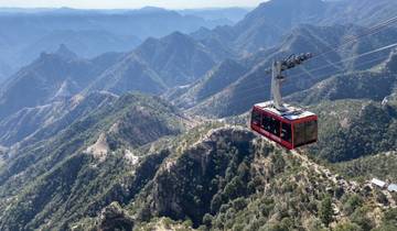 Cable car traveling over a rugged mountain landscape.