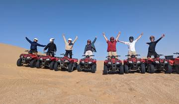 Group of people on quad bikes over a desert landscape.