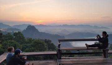 People enjoying a stunning sunset view over mountains and mist.