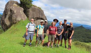 Group of hikers posing on a grassy trail with rocky outcrops.