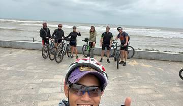 Group of cyclists posing on a coastal promenade.