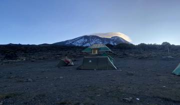 Tents at a campsite with Mount Kilimanjaro in the distance.