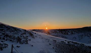 Sunset over a snowy mountainous terrain.