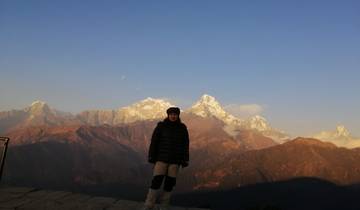 Person standing on a hill with a view of the Himalayas.