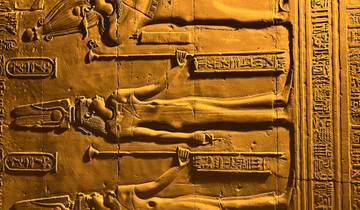 Illuminated ancient Egyptian carvings on a wall.