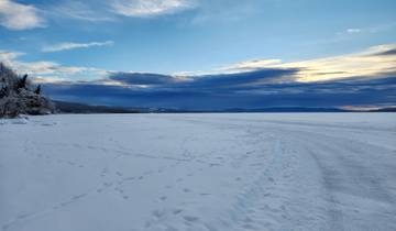 Snowy landscape with a road leading towards distant snow-covered mountains.