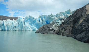 Impressive glacier next to a lake under a clear sky.