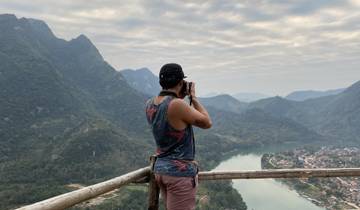 Person taking photos of a scenic hilly landscape with a river.