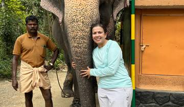 Person posing with an elephant in a rural setting.