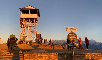 Tourists at Poon Hill viewpoint with mountains in the distance.
