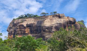 The Sigiriya Rock with trees below under a clear blue sky.