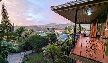 A scenic view from a terrace overlooking a lush green valley at sunset.