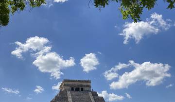 Pyramid top with a bright blue sky and fluffy white clouds.