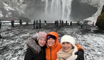 Group of people in front of a large waterfall with snow.